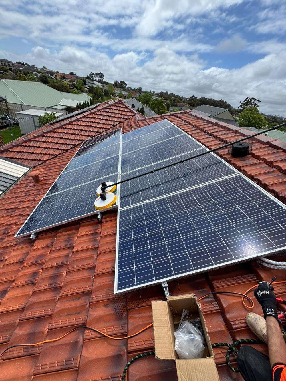 Rotating brush cleaning panels on a tile roof